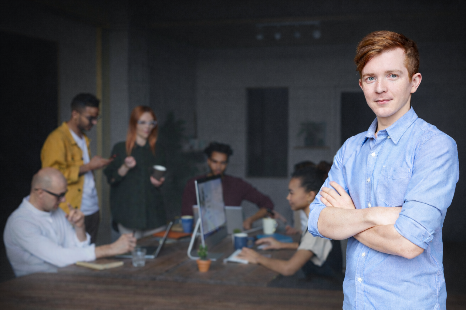 Professional standing alongside a team collaborating around a table